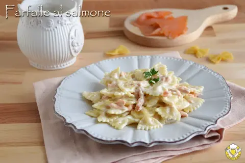 Farfalle al salmone cremose, un piatto invitante con pasta a forma di farfalla e pezzetti di salmone affumicato, guarnito con prezzemolo fresco.