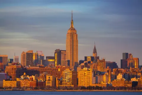Zachód słońca nad Manhattanem, z Empire State Building i Chrysler Building w tle. Zastanawiasz się, ile się leci do Nowego Jorku?
