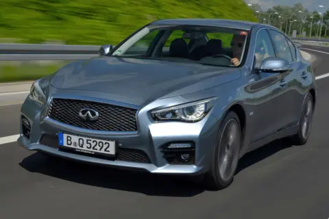 Srebrny infiniti samochód pędzi po autostradzie, kierowca w okularach przeciwsłonecznych cieszy się jazdą.