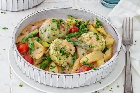 Spargel mal anders: cremiger Eintopf mit Klößen, Kartoffeln, Kirschtomaten und grünen Bohnen, garniert mit Petersilie.