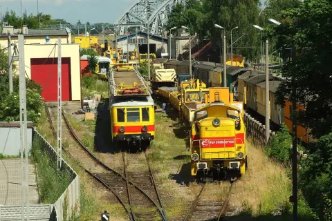 Dwie żółte lokomotywy, jedna z napisem "PKP Energetyka", stoją na torach w słoneczny dzień.