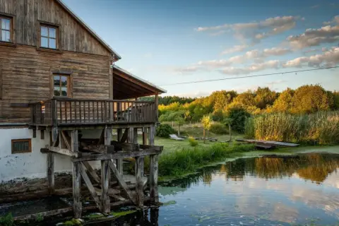Drewniany młyn nad wodą, otoczony zielenią. Idealne miejsce na weekendowe wypady, szukając fajnych miejsc niedaleko Warszawy.