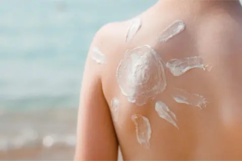 Sonnenschutz auf dem Rücken eines Kindes, geformt wie eine Sonne. Die astaxanthin wirkung schützt die Haut vor der Sonne.