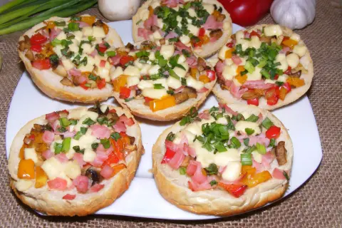 Pyszny farsz do zapiekanek na bułkach: kolorowe papryki, szynka, pieczarki i ser, posypane szczypiorkiem.