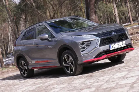 Szary Mitsubishi Eclipse Cross EV na leśnej drodze. Wiele pozytywnych mitsubishi eclipse cross opinie potwierdza jego wszechstronność.