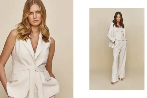 Elegancka stylizacja z białą marynarką bez rękawów i szerokimi spodniami. Druga modelka prezentuje komplet z białą marynarką.