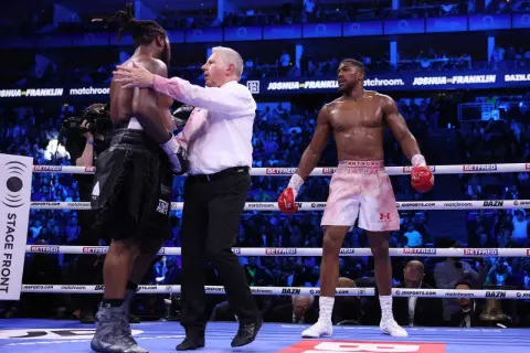 Referee separates boxers after a round. The crowd watches, anticipating how many knockdowns in boxing will occur next.