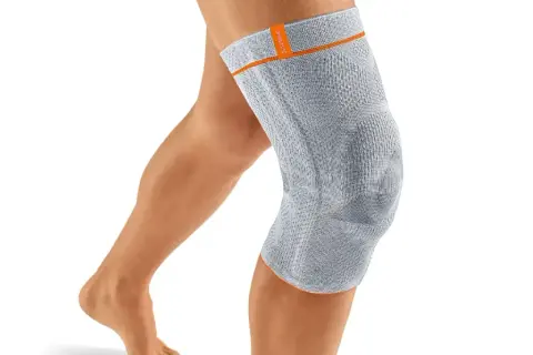 Ein Bein mit einer grauen Kniebandage. Die Bandage könnte bei falscher Anwendung oder zu engem Sitz Schmerzen verursachen.