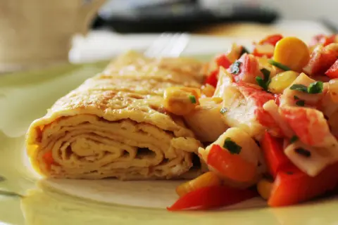 Zrolowany omlet po japońsku z kolorową sałatką z warzyw i surimi.