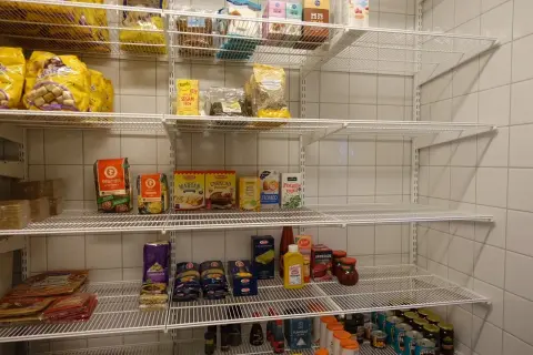 Hylla med basvaror att ha hemma: mjöl, pasta, krossade tomater, senap, sesamfrön och mer.