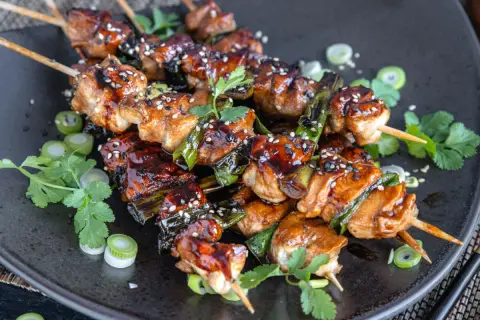 Leckeres Yakitori: saftige Hähnchenspieße mit Teriyaki-Glasur, garniert mit Sesam und Frühlingszwiebeln.