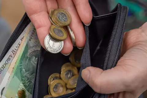 Dłoń z monetami i banknotami w portfelu. Zastanawiasz się, ile wynosi renta wojskowa?