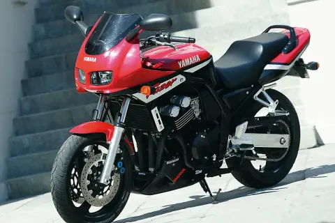 Czerwony motocykl Yamaha Fazer 600 z czarnym siedzeniem i owiewką, zaparkowany na zewnątrz.