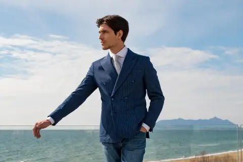 Uomo elegante con abito doppiopetto blu a righe, perfetto come invitato a una cerimonia estiva.