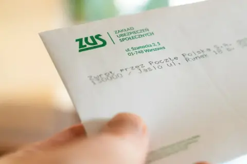 Dłoń trzyma kopertę ZUS. Może to zwrot środków, np. 500 plus dla niepełnosprawnych.