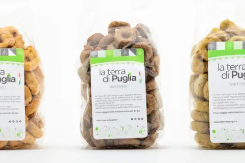 Tre sacchetti trasparenti pieni di taralli salati pugliesi, con etichette che celebrano i sapori autentici della Puglia.