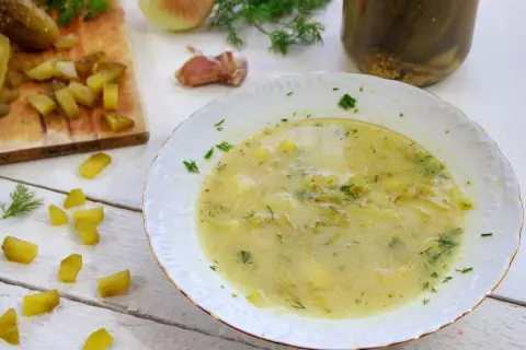 Zupa ogórkowa przepis babci, pachnąca koperkiem i czosnkiem, z kawałkami ogórków na desce i w słoiku.