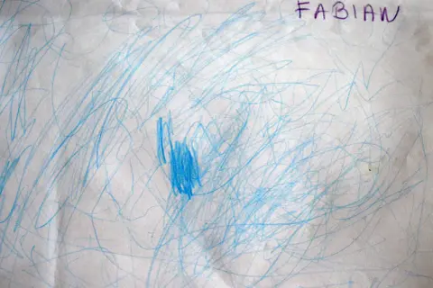 Niebieskie bazgroły na papierze, podpisane "FABIAN". To początkowe etapy rysunku dziecka, pełne ekspresji i wyobraźni.