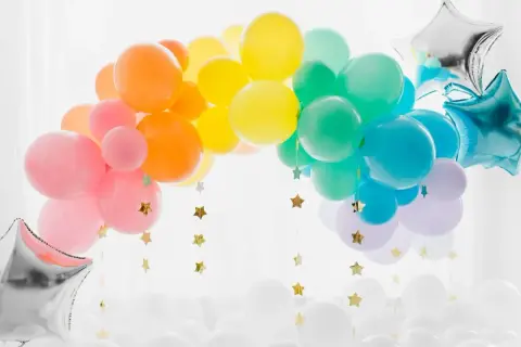 Arc-en-ciel de ballons colorés, une idée déco avec ballon à gonfler pour une fête joyeuse. Étoiles dorées suspendues.