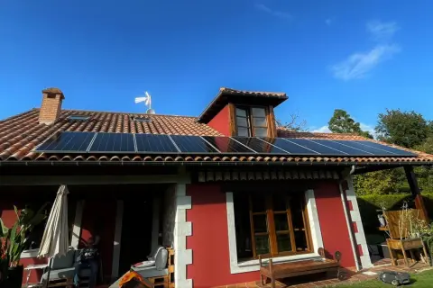 Instalación de placas solares en tejado rojo de casa en Asturias. Aprovecha la subvención para energía limpia.
