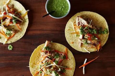 Tre färdiga tacos med kyckling, grönsaker och grön sås. Ett enkelt tacos recept för en god middag.