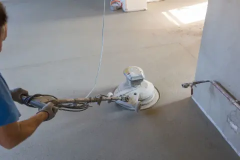 Lavoratore leviga massetto con monospazzola. Preventivo costo rifacimento massetto e pavimento.