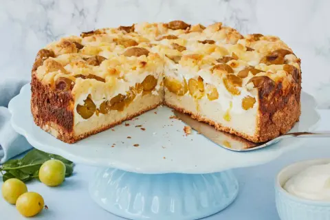 Saftiger Mirabellenkuchen mit Quark und Streuseln auf einem blauen Tortenständer.