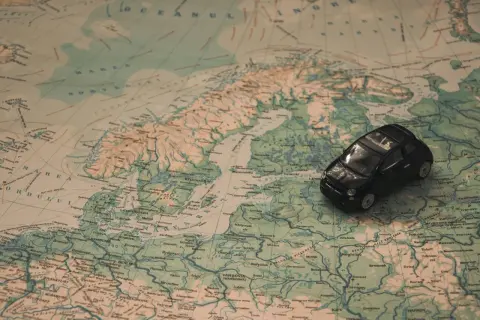 Czarny Fiat 500 na mapie Europy, sugerujący podróż do Włoch samochodem.