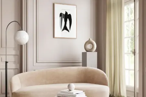 Ein gemütliches Wohnzimmer in greige farbe mit einem geschwungenen Sofa, einem modernen Stehlampen und einem Kunstwerk mit einem Vogel.
