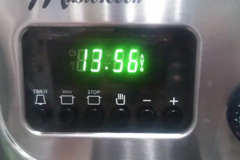 Cyfrowy wyświetlacz piekarnika Mastercook pokazuje godzinę 13:56. Ikony sugerują funkcje timera, gotowania, stopu i automatycznego trybu.