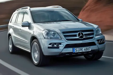 Srebrny Mercedes-Benz GL Class pędzi po drodze, za nim rozmyte krajobrazy.
