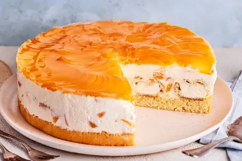 Ein köstliches Windbeuteltorte Rezept: saftiger Boden, cremige Füllung mit Windbeuteln und Pfirsichspalten, überzogen mit glänzendem Pfirsichgelee.