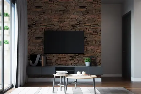 Un salon moderne avec un mur en pierre texturé derrière une TV. Des tables basses en bois et des plantes apportent une touche chaleureuse.