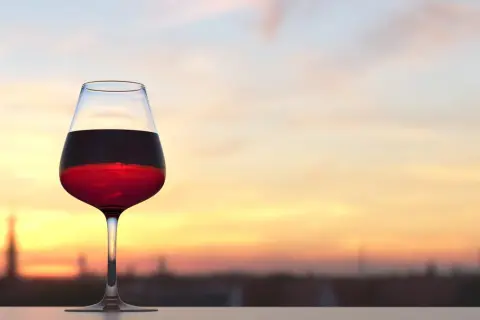 Calice di vino rosso al tramonto, con la sua acidità totale che si percepisce anche visivamente.