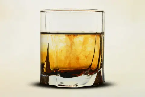 Szklanka z bursztynowym płynem, w którym rozpuszcza się barwnik. Wizualizacja procesu, jak zrobić whisky w domu.