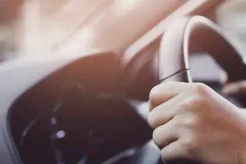 Manos sujetando el volante de un coche, con un ligero ruido al girar el volante.