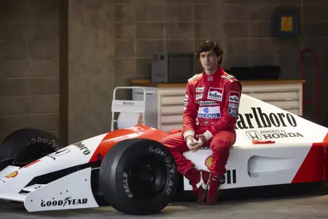 Młody kierowca w czerwonym kombinezonie siedzi na bolidzie F1. Czy to przyszły były brazylijski kierowca formuły 1?