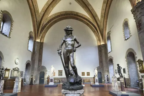 Bronzene Statue von David in Florenz, ein Meisterwerk der Renaissance, steht in einem Museumssaal unter kunstvollen Gewölben.