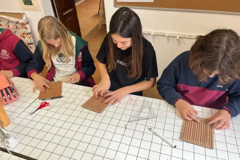 Chicas concentradas en una actividad manual, aprendiendo sobre el IGCSE que es y cómo aplicarlo en proyectos creativos.