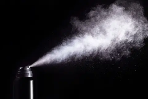 Chmura białego pyłu wydobywa się z czarnego aerozolu. Czy gaz pieprzowy działa na psy? To pytanie budzi kontrowersje.