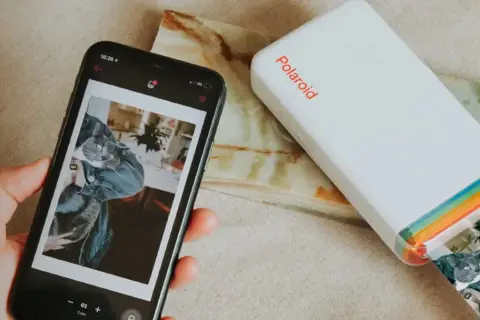 Jak wydrukować zdjęcie z telefonu? Smartfon z kotem i drukarka Polaroid w akcji.