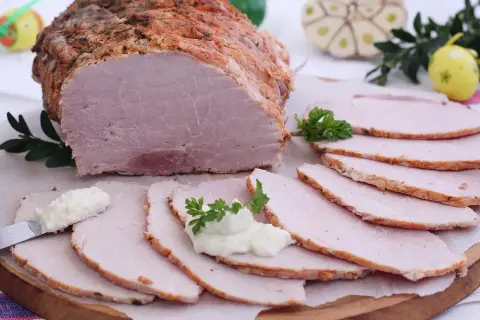 Pyszna szynka pieczona na obiad, pokrojona w plastry, podana z chrzanem i ziołami. Idealna na rodzinny posiłek.