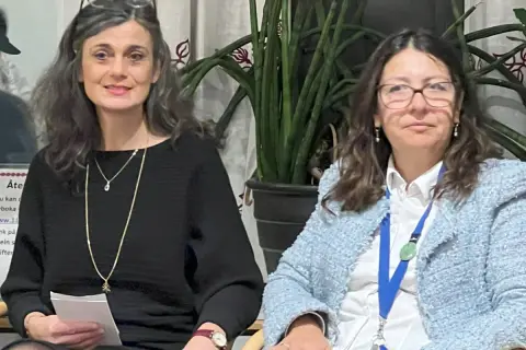 Elisabeth Punzi, till vänster, ler med glasögon på huvudet. Bredvid henne sitter en kvinna i ljusblå kavaj.