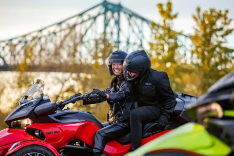 Para jadąca na czerwonym Can-Am Spyder, w tle most i jesienne drzewa.