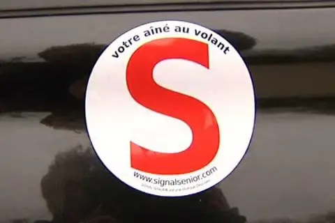Macaron "votre aîné au volant" sur une voiture. Le S rouge est bien visible.