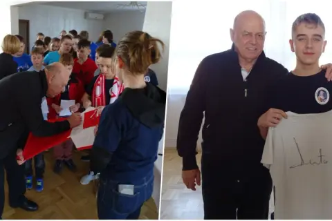 Starszy mężczyzna podpisuje koszulkę dla grupy dzieci, a potem pozuje z młodym chłopcem trzymającym podpisaną koszulkę.