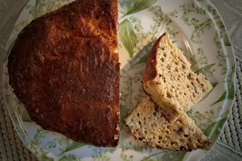 Chleb keto z twarogu i jajek, pyszny i puszysty, pokrojony na talerzu z konwaliami.