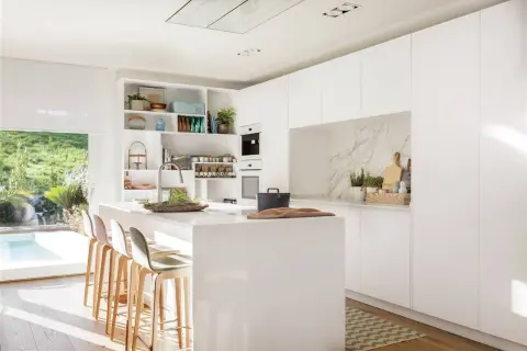 Cocina moderna y luminosa con isla central, taburetes y estanterías. Ideas de diseño cocina minimalista y funcional.