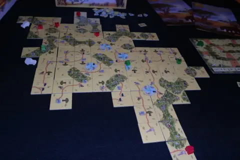 Plansza do gry Carcassonne: Safari. Rozłożone kafelki tworzą mapę sawanny z drogami i zwierzętami.