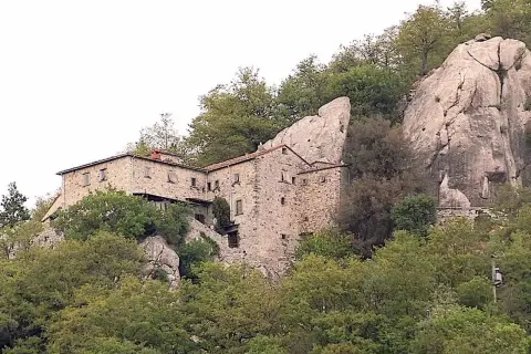 Antica pieve in pietra a Pieve Santo Stefano, incastonata tra rocce e alberi secolari, testimone di storia.